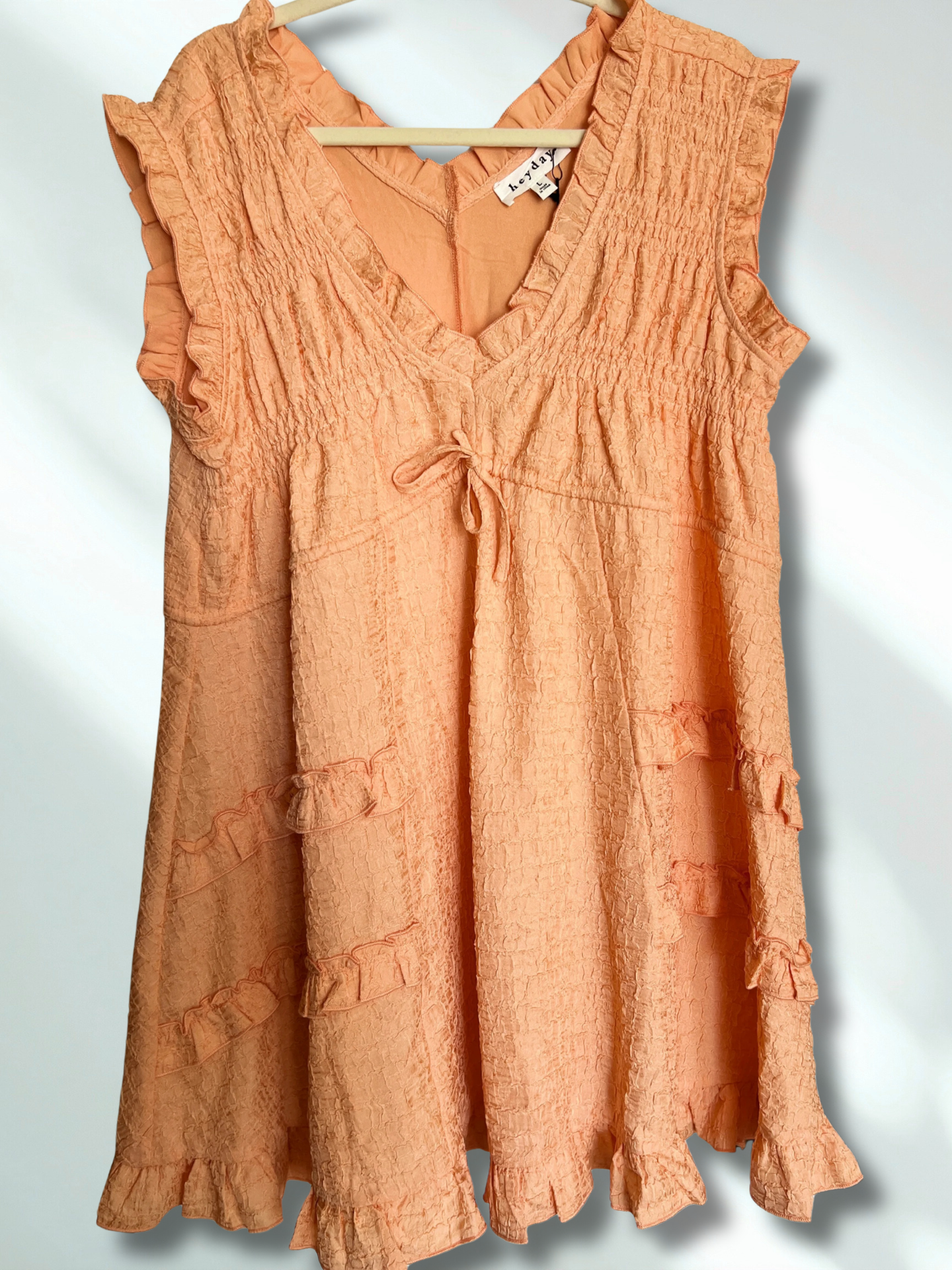 Peach-colored dress with ruffled details on a white background