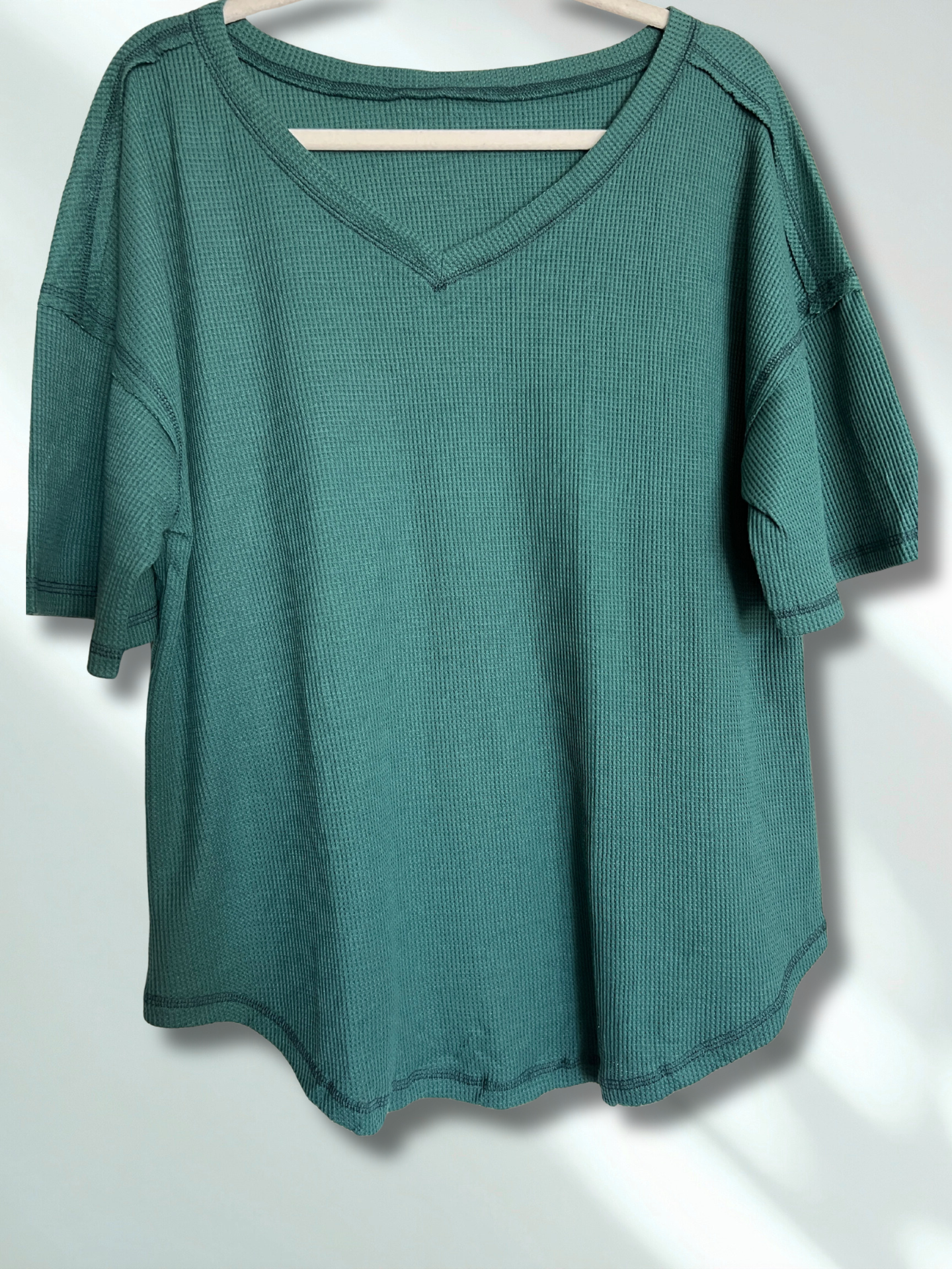 Green textured shirt on a hanger against a white background