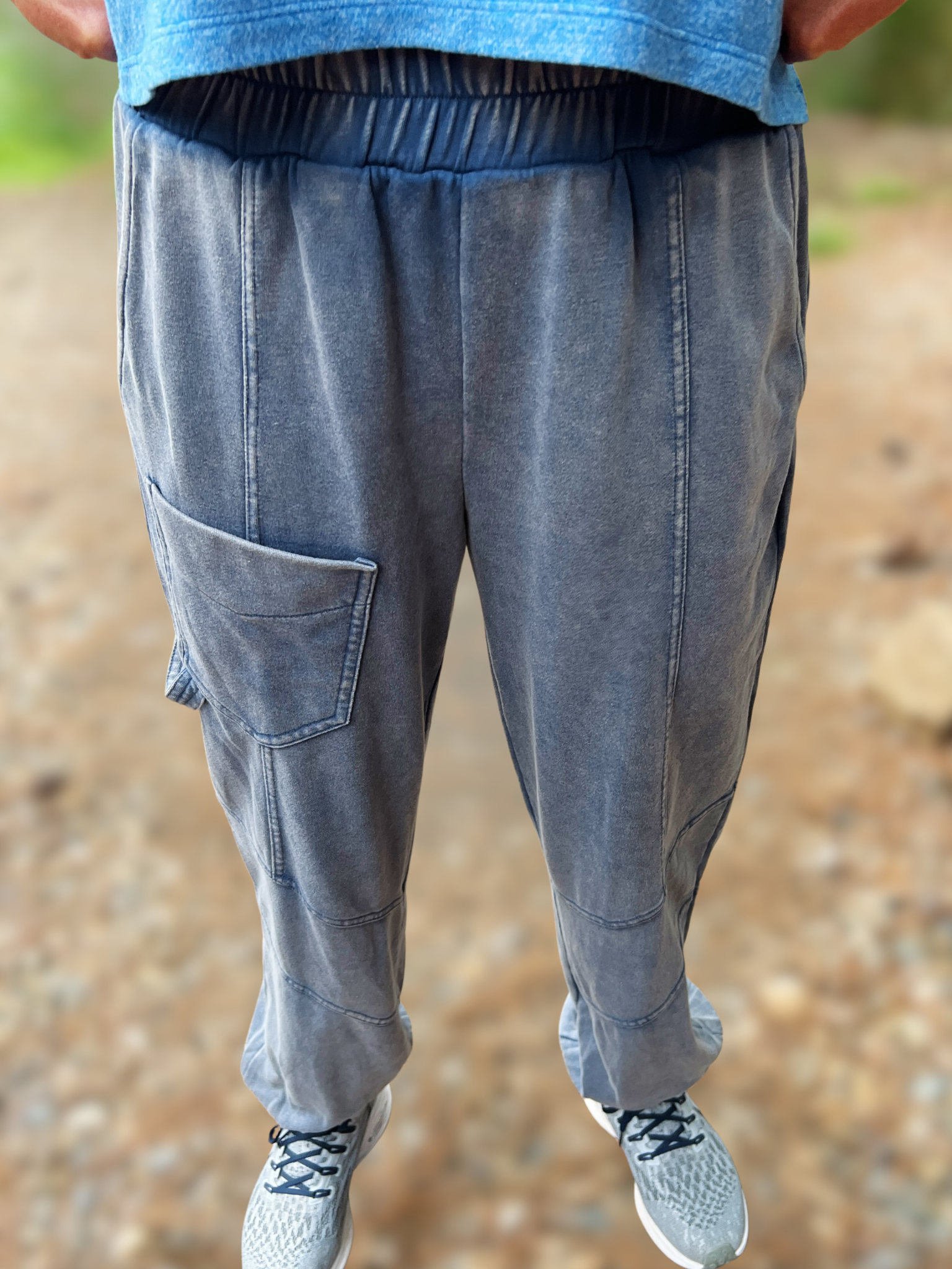 Person wearing gray jogger pants with a blurred natural background
