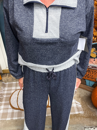 Person wearing a gray and white fleece pullover with matching pants indoors.