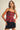 A woman wearing a red tartan plaid camisole top with thin black straps and a drawstring detail, paired with a black mini skirt. The top features a fitted bodice with a peplum ruffle at the waist.