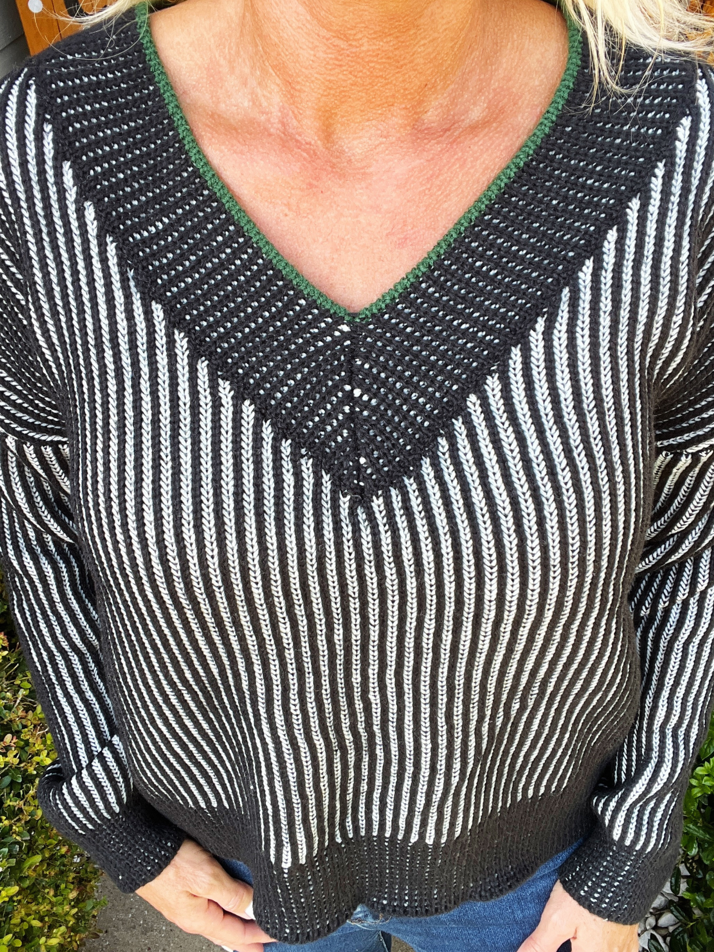 Person wearing a black and white striped sweater with green trim.