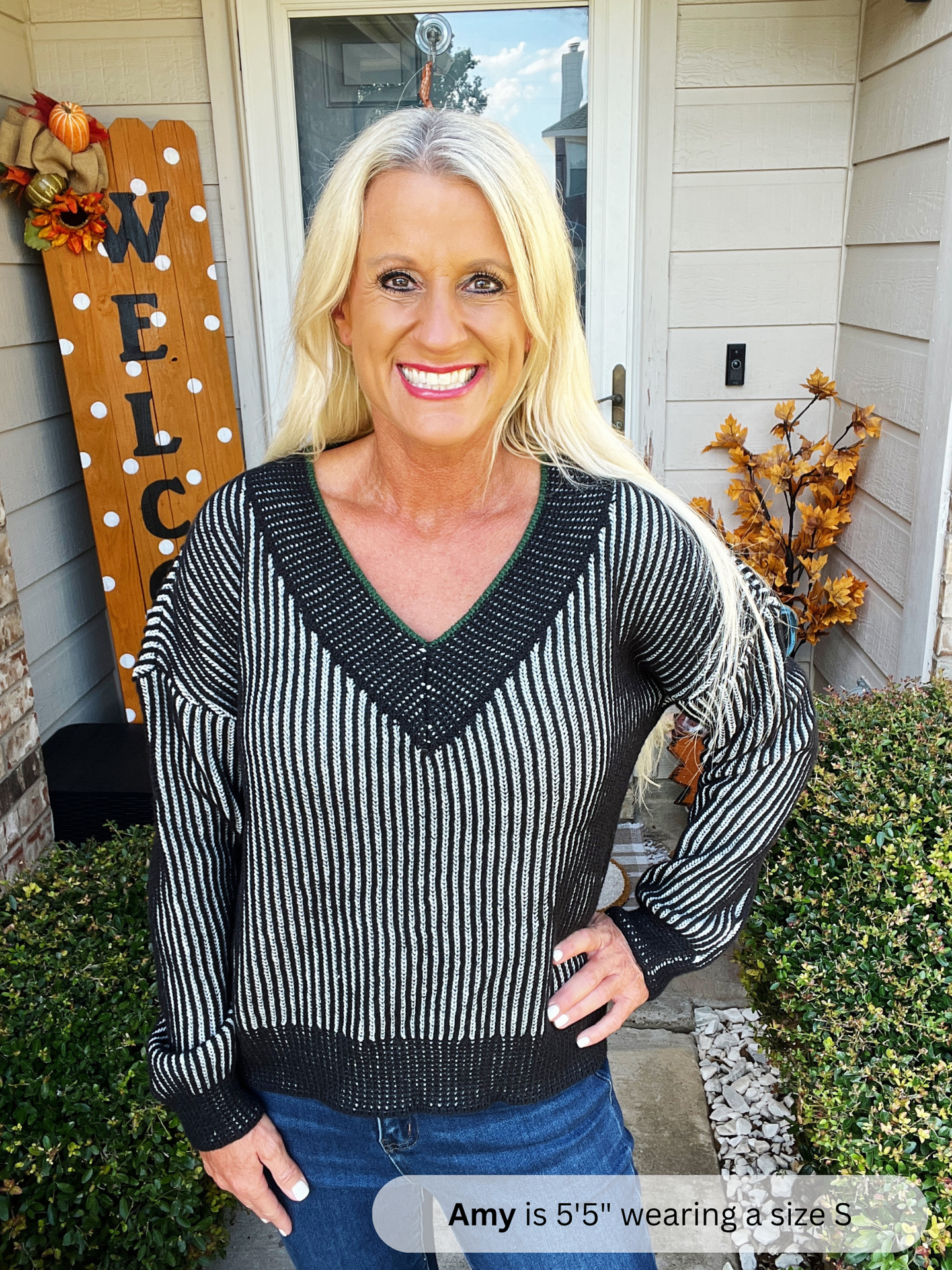 Woman wearing a black and white striped sweater standing outside a house with decorative elements.