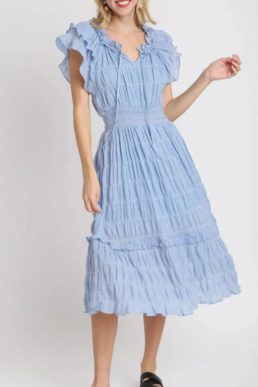 Woman wearing a light blue dress with ruffled sleeves on a white background