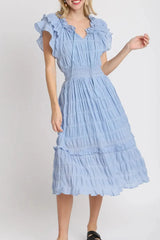 Woman wearing a light blue dress with ruffled sleeves on a white background