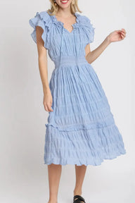Woman wearing a light blue dress with ruffled sleeves on a white background
