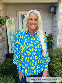 Woman wearing a blue shirt with yellow patterns standing outside a house.