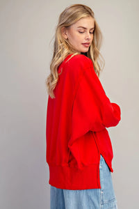 A woman wearing an oversized red cardigan with a relaxed fit, shown from the back, paired with light blue denim jeans. The cardigan features a classic button-front design and dropped shoulders.