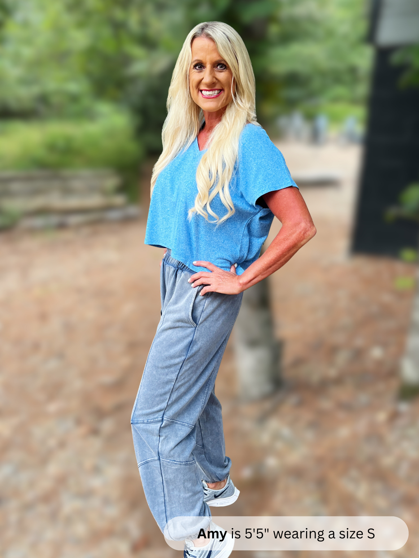 Woman wearing a blue top and gray sweatpants standing outdoors with text indicating her height and shoe size.