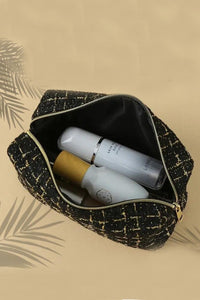 A black and gold quilted cosmetic bag with a geometric pattern lies open on a beige background, revealing white skincare bottles and a gold jar inside. The bag features a black interior lining and a gold zipper closure.