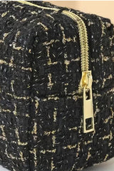 A black and gold tweed jacket with a textured weave pattern, featuring a gold-tone zipper and black accent details on the front closure.