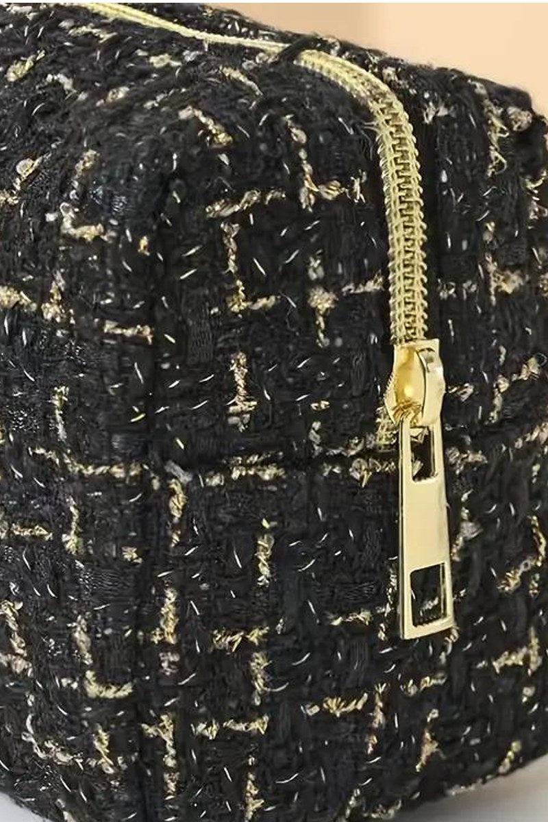 A black and gold tweed jacket with a textured weave pattern, featuring a gold-tone zipper and black accent details on the front closure.