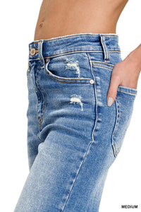 Close-up side view of medium-wash distressed blue jeans with ripped details on the thighs, featuring a classic five-pocket design and white contrast stitching.