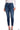 A woman wears dark blue cropped skinny jeans with a high waist and classic five-pocket styling, paired with a white ribbed long-sleeve top and black strappy heels.