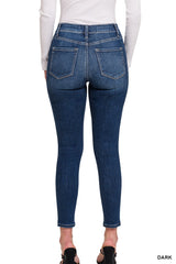 Woman wearing dark blue skinny jeans with a high waistband and cropped ankle length, shown from behind to display the fitted silhouette and back pocket details.