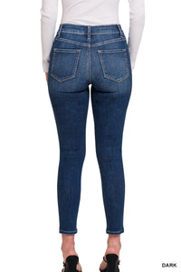 Woman wearing dark blue skinny jeans with a high waistband and cropped ankle length, shown from behind to display the fitted silhouette and back pocket details.