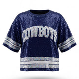A navy blue sequined short-sleeve sweatshirt featuring "COWBOYS" in white and silver lettered appliqué across the chest, with matching silver sequined stripes on the sleeves and hem.