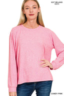 A woman wearing a candy pink soft melange long-sleeve crew neck top paired with dark blue jeans, showcasing the relaxed fit and comfortable texture of the garment.