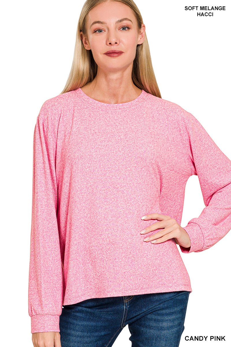 A woman wearing a candy pink soft melange long-sleeve crew neck top paired with dark blue jeans, showcasing the relaxed fit and comfortable texture of the garment.