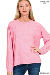A woman wearing a candy pink soft melange long-sleeve crew neck top paired with dark blue jeans, showcasing the relaxed fit and comfortable texture of the garment.