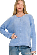 A woman wearing a cornflower blue ribbed long-sleeve top with a crew neckline and vertical seam detail down the front, paired with blue jeans.