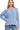 A woman wearing a cornflower blue ribbed long-sleeve top with a crew neckline and vertical seam detail down the front, paired with blue jeans.