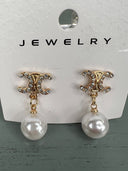 Pair of dangling pearl earrings with ornate gold-tone studded tops featuring a decorative scrolled design and smooth white pearl drops suspended by delicate chain links.