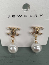 Pair of dangling pearl earrings with ornate gold-tone studded tops featuring a decorative scrolled design and smooth white pearl drops suspended by delicate chain links.
