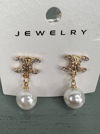 Pair of dangling pearl earrings with ornate gold-tone studded tops featuring a decorative scrolled design and smooth white pearl drops suspended by delicate chain links.
