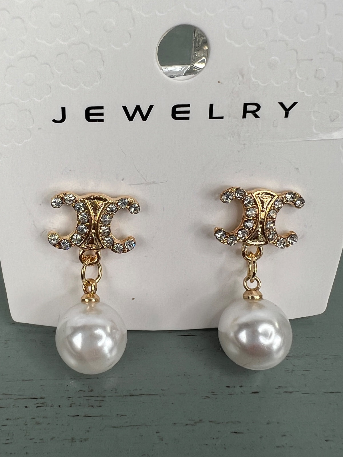 Pair of dangling pearl earrings with ornate gold-tone studded tops featuring a decorative scrolled design and smooth white pearl drops suspended by delicate chain links.