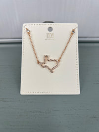 Rose gold-toned necklace with a delicate wavy heart pendant outlined in small crystals, displayed on a cream-colored rectangular jewelry card with decorative perforated border.