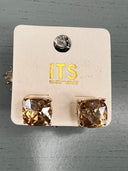 A pair of rose gold-toned stud earrings featuring large square-cut champagne or golden-brown crystals, displayed on a cream-colored ITS brand card with matching crystal accent studs shown above.