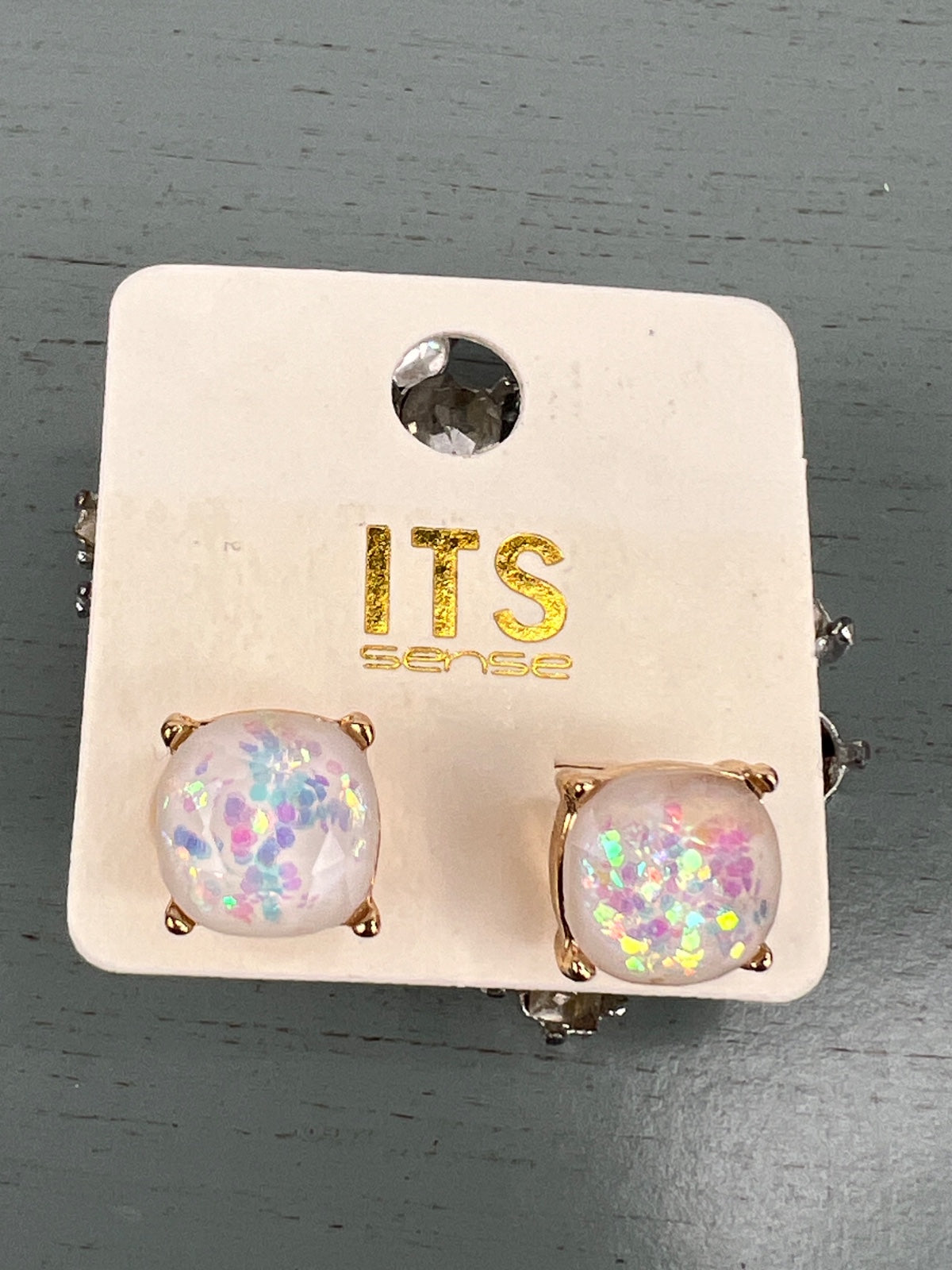 Pair of stud earrings with rose gold-toned settings, each featuring a clear dome filled with colorful iridescent confetti in pink, purple, and blue hues. The earrings are displayed on a cream-colored ITS Genie brand card with a decorative rhinestone accent at the top.