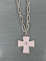 A silver-toned chain necklace featuring oval link segments, suspending a rectangular cross pendant with decorative dot details and a central oval medallion, displayed on a gray wooden background.