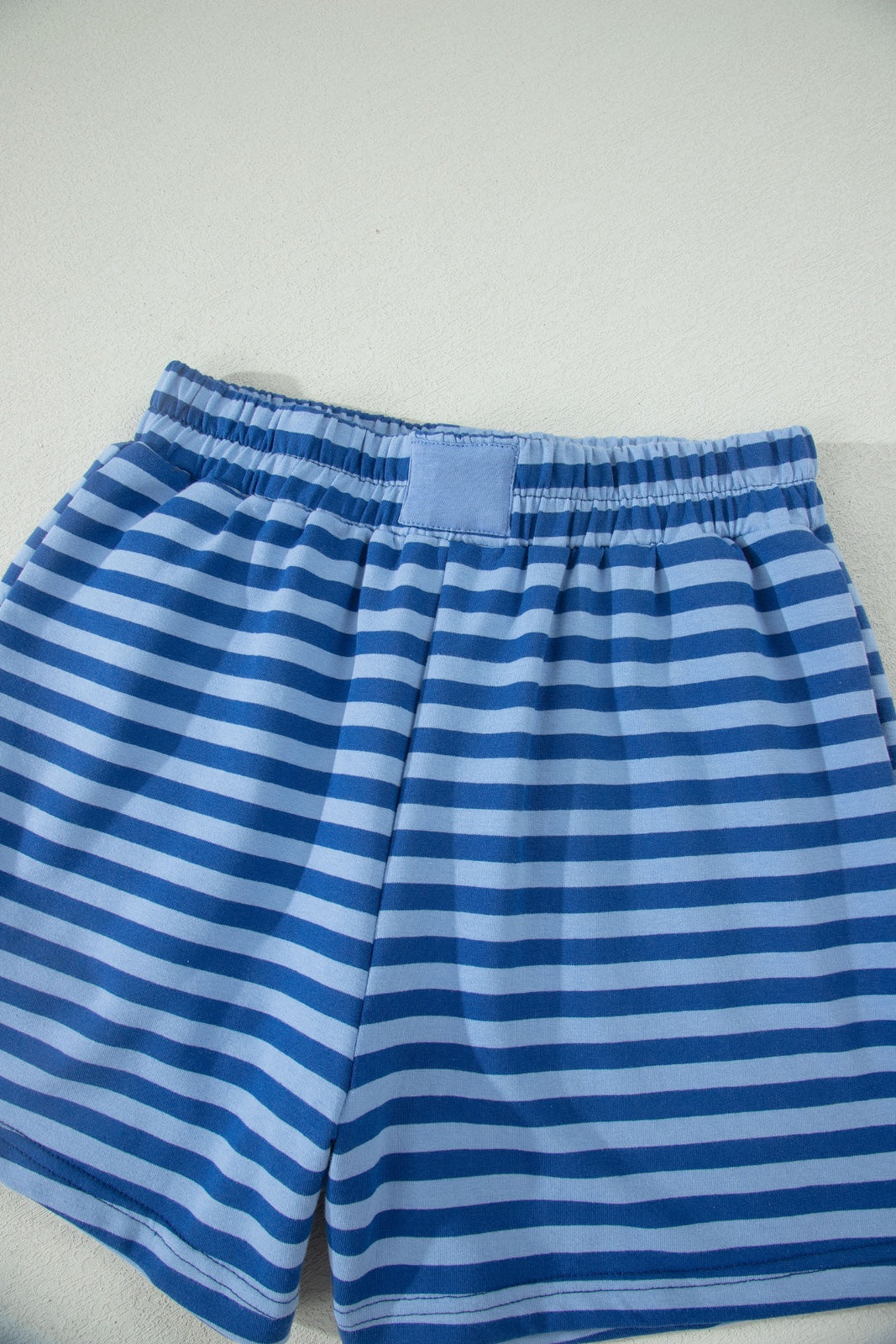 Blue and white horizontal striped shorts with an elastic waistband and drawstring, displayed flat on a white background.