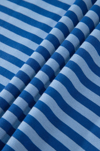 Close-up of a blue and white striped fabric with horizontal stripes in alternating dark and light blue tones, showing the textured weave and dimensional folds of the material.