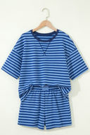 A children's two-piece set featuring a blue and light blue striped short-sleeved shirt with a crew neckline, paired with matching striped shorts with an elastic waistband, displayed on a wooden hanger against a cream background.
