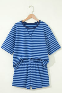 A children's two-piece set featuring a blue and light blue striped short-sleeved shirt with a crew neckline, paired with matching striped shorts with an elastic waistband, displayed on a wooden hanger against a cream background.