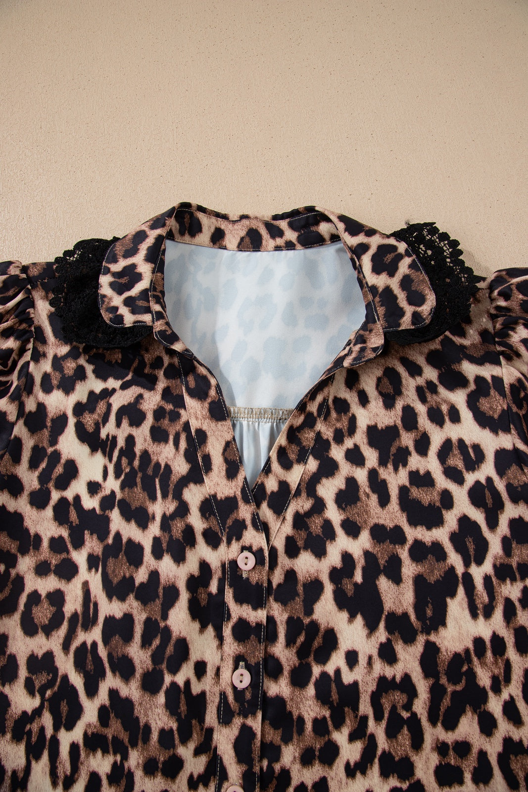 Leopard print blouse with puffed black ruffled sleeves and a light blue collar, featuring white button closures down the front.