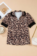 A leopard print short-sleeve shirt with a button-front closure and black ruffled collar and cuffs, displayed flat lay on a beige background alongside accessories including a white crossbody bag and sunglasses.