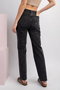 Woman wearing high-waisted black straight-leg jeans with a cropped tan top and cork sandals, shown from behind to display the classic five-pocket denim styling and relaxed fit.