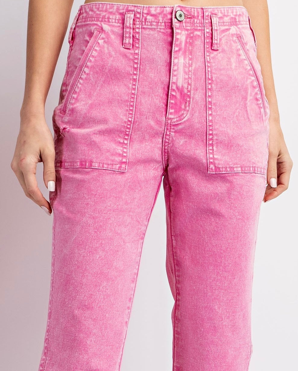 Pink acid-wash denim pants with a high waist, front patch pockets, and a straight-leg silhouette. The jeans feature decorative topstitching and a silver button closure.