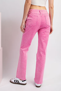 A model wears bright pink straight-leg jeans with visible stitching and back pockets, paired with a white crop top and white sneakers with black stripes, shown from the back.