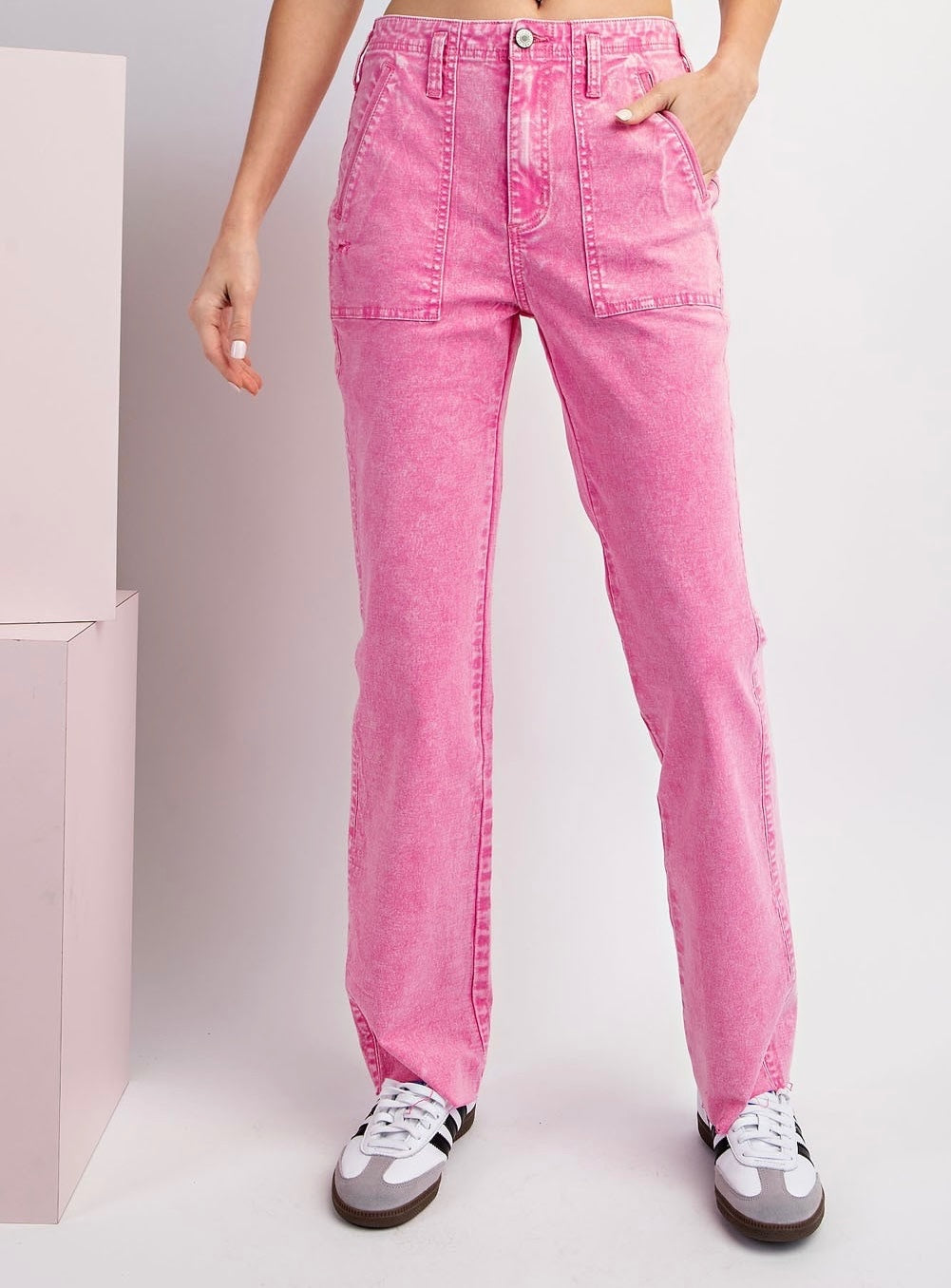 A model wearing pink acid-wash straight-leg jeans with cargo pockets and a high waist, styled with white and gray sneakers.