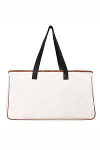 A large cream and tan tote bag with brown leather trim along the top and bottom edges, featuring two black fabric handles for carrying.