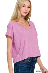 A woman wearing a bright mauve short-sleeved v-neck t-shirt paired with dark blue jeans, shown from the shoulders down against a white background.