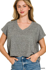 A woman wearing a heathered gray short-sleeved v-neck t-shirt paired with blue jeans, standing against a white background. The casual tee features a relaxed fit and textured fabric.