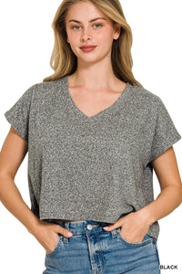 A woman wearing a heathered gray short-sleeved v-neck t-shirt paired with blue jeans, standing against a white background. The casual tee features a relaxed fit and textured fabric.