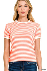 A woman wearing a coral and white striped short-sleeve crew neck t-shirt paired with dark denim jeans, standing against a white background.