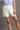 A woman wearing cream-colored ribbed shorts with an elastic waistband, paired with a light blue ruffled short-sleeve top.